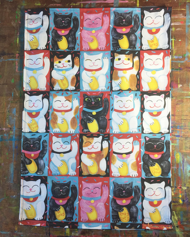 a tea towel of Lucky Cats on an artist's desk
