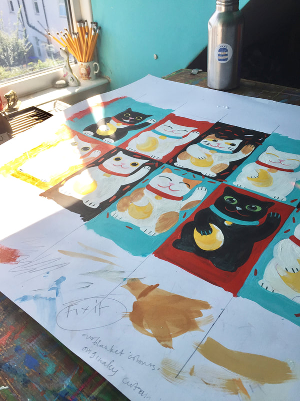 an unfinished design of Lucky Cats on an artist's desk