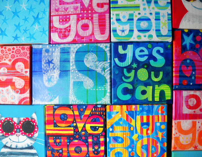 Various paintings on canvas with slogans Yes You Can, Love You, Be Kind, Us by Jo Brown.